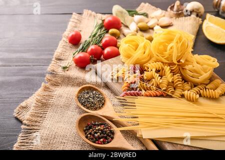 Pasta diversa cruda con spezie e verdure sul tavolo Foto Stock