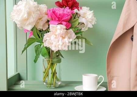 Vaso con bellissimi fiori di pony su rack su sfondo colorato Foto Stock