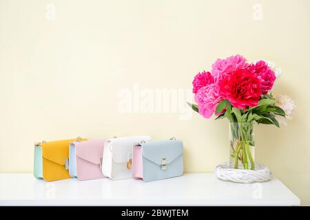 Vaso con bellissimi fiori di pony con borse sul tavolo in camera Foto Stock