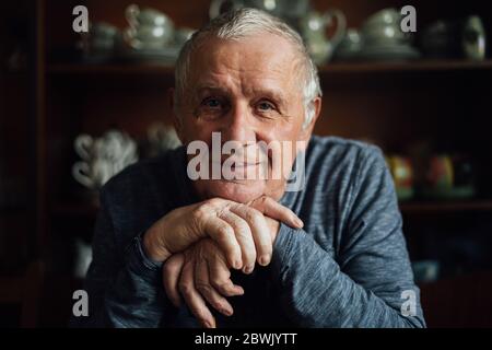 Uomo anziano con bastone da passeggio seduto a casa. Ritratto di vecchio negli anni 80. Foto Stock