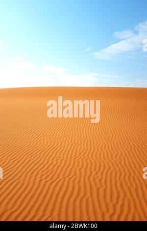 Il motivo di sabbia desertica arancione brillante si increspa e il cielo blu chiaro per un caldo backgroun estivo. Foto Stock