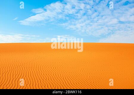 Il motivo di sabbia desertica arancione brillante si increspa e il cielo blu chiaro per un caldo backgroun estivo. Foto Stock