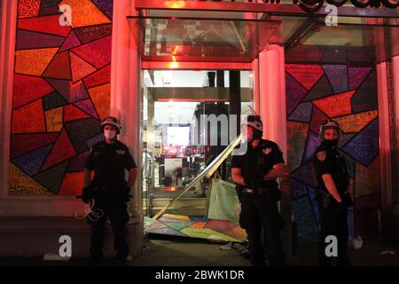 31 maggio 2020, New York, New York, USA: Giorno di pacifiche marce di New York lascia il posto al caos dopo il buio dopo il quarto giorno di proteste contro deathÃ‚Â ofÃ‚Â George Floyd.Ã‚Â saccheggiatori hanno assalito Lower Manhattan, distruggendo più negozi, Ã‚Â rubando oggetti, Ã‚Â accendendo incendi, Ã‚Â e scontrandosi con la polizia tutta la notte. Questi tre agenti di polizia si sono presi le posizioni davanti al negozio di lusso Bloomingdales che è stato vandalizzato. Funzionari e polizia credono che sia il risultato di gruppi ben organizzati infiltrando proteste pacifiche, trasformandole in una rivolta.Ã‚Â il NYPD ha arrestato più di 250 persone. New York Foto Stock