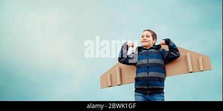 Concetto di infanzia felice. Sogni di volare. Bambino con ali di aereo Foto Stock