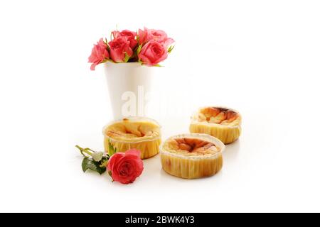 torte o muffin fatti in casa e un vaso con rose rosa isolato con ombre su sfondo bianco, spazio copia, fuoco selezionato, profondità ridotta Foto Stock