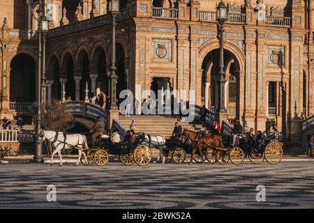 Siviglia, Spagna - 17 gennaio 2020: Tour della città in carrozze trainate da cavalli in Plaza de España, una piazza nel Parque de María Luisa, a Siviglia, Spagna, costruito Foto Stock