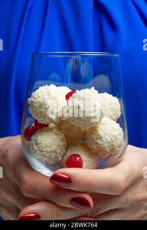 Tartufi di cocco bianchi in bicchiere di vino con foglie di menta. Donne che tengono un bicchiere di vino con biscotti al cocco. Foto Stock