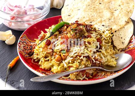 Pollo indiano halal o Biryani di montone servito con raita di pomodoro di yogurt su sfondo bianco. Messa a fuoco selettiva. Foto Stock