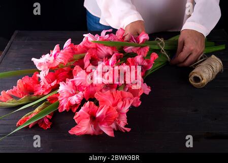 Le mani delle donne creare un mazzo di fiori di gladiolus per il giorno di San Valentino su un regalo Foto Stock