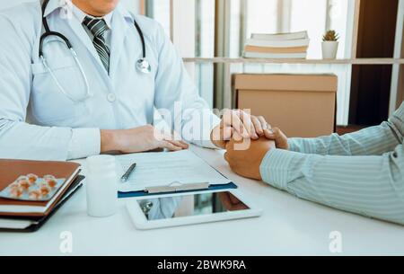 Il medico scosse le mani e consolò i pazienti che erano preoccupati per il trattamento. Foto Stock