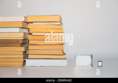 Stack di libri, unità disco rigido e scheda di memoria, sviluppo di tecnologia e capacità di memorizzazione. Dati di storage, informazioni compresse, digitale versus Foto Stock