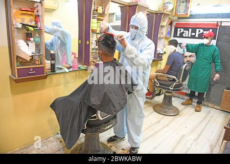 Beawar, Rajasthan, India - 1 giugno 2020: Barbiere indossare dispositivi di protezione individuale (PPE) assiste un cliente al suo salone, il primo giorno di COVID-19 blocco 5.0, a Beawar. Credit: Sumit Saraswat/Alamy Live News Foto Stock