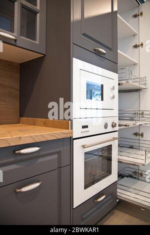 Interni di lussuose attrezzature da cucina moderne in legno e armadi bianchi grigi Foto Stock