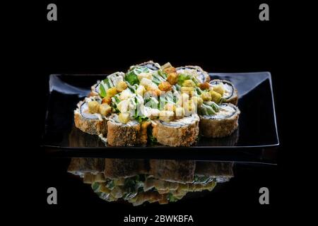 Un primo piano di panini fritti di sushi di cibo isolato su nero. Riflessione Foto Stock