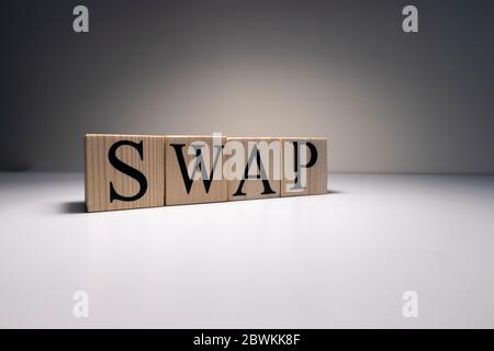 La parola swap è stata scritta con cubetti di legno. Primo piano dei faretti e su un tavolo bianco. Primo piano. Foto Stock