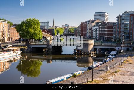 Bristol, Inghilterra, Regno Unito - 25 maggio 2020: Un ciclista attraversa il ponte Redcliffe, mentre la luce scende sulle banchine e sugli edifici dell'Harbo galleggiante di Bristol Foto Stock