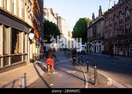 Bristol, Inghilterra, Regno Unito - 25 maggio 2020: Due ciclisti passano su una pista ciclabile protetta su Baldwin Street nel centro di Bristol. Foto Stock