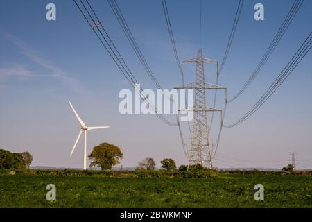 Le turbine eoliche si trovano nei campi agricoli accanto alle linee elettriche ad alta tensione National Grid vicino ad Alveston, nel Gloucestershire meridionale. Foto Stock