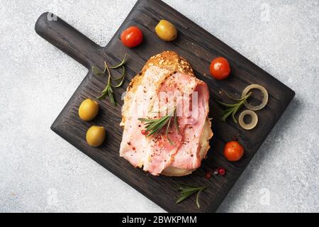 Panini con pane integrale con formaggio cremoso, pancetta su un tagliere di legno. Sfondo grigio calcestruzzo spazio di copia Foto Stock