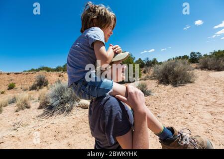 Ragazza di 14 anni che dà al fratello minore un giro in piggyback, Galisteo Basin, NM. Foto Stock