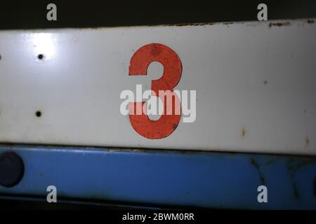 Vecchio vintage mano dipinta rosso colorato numero 3 su sfondo bianco blu stagno metallo Foto Stock