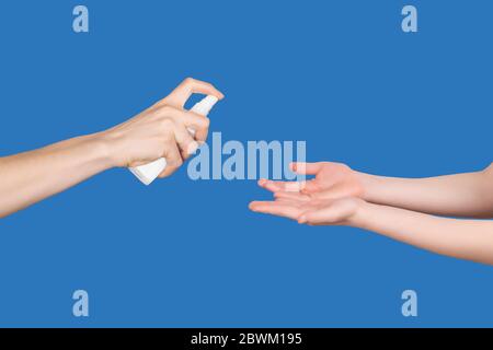 Donna spruzzare le mani del bambino con uno spray a base di alcol per il lavaggio delle mani come misura preventiva di igiene contro l'infezione da coronavirus. Uso di antibatterico h Foto Stock