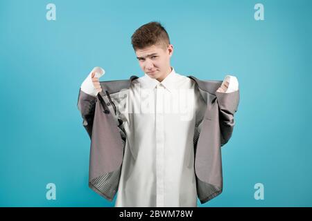 il ragazzo guarda tristemente la macchina fotografica mentre indossa abiti da ufficio per adulti. Foto Stock