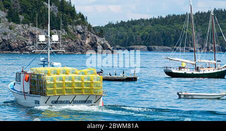 Bar Harbor, Maine, USA - 28 luglio 2017: Una barca da pesca sta andando fuori pieno di trappole di aragosta gialla a Portland, Maine, con le isole Porcupine alle spalle Foto Stock