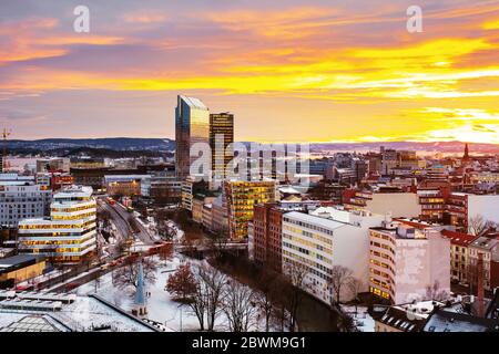 Oslo, Norvegia. Una vista notturna della zona di Sentrum di Oslo, Norvegia, con edifici moderni e storici e il traffico di auto. Tramonto cielo colorato in inverno con s. Foto Stock