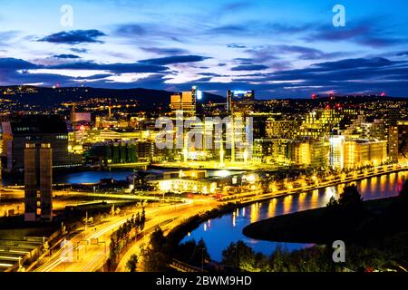 Oslo, Norvegia. Una vista notturna della zona del Sentrum di Oslo, Norvegia, con edifici con codice a barre e il fiume Akerselva. Cantiere con cielo colorato al tramonto Foto Stock