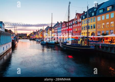 Copenaghen, Danimarca. Vista della famosa area di Nyhavn nel centro di Copenhagen, Danimarca in serata. Varie barche ormeggiate con edifici storici e cl Foto Stock
