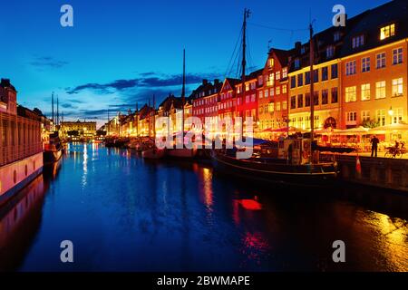 Copenaghen, Danimarca. Vista della famosa area di Nyhavn nel centro di Copenhagen, Danimarca di notte. Varie barche ormeggiate con edifici storici e clou Foto Stock