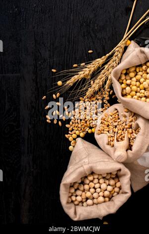 Piccoli sacchetti con vari cereali e cereali sul tavolo di legno, vista dall'alto, spazio di copia Foto Stock