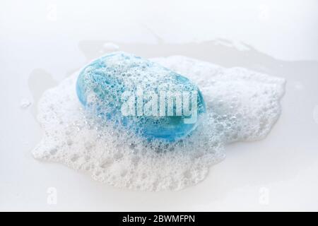 bar di sapone blu con un sacco di schiuma e bolle su uno sfondo bianco, salute e concetto di igiene contro l'infezione da coronavirus, copia spazio, sele Foto Stock