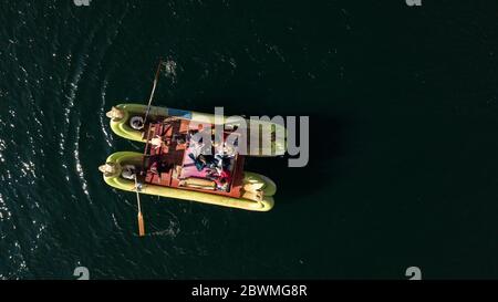 Primo piano dall'alto sulla tradizionale barca Uros realizzata con la pianta Totora con turisti a bordo, gente del posto che si addormica e splende il sole. Foto Stock