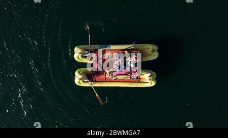 Primo piano dall'alto sulla tradizionale barca Uros realizzata con la pianta Totora con turisti a bordo, gente del posto che si addormica e splende il sole. Foto Stock