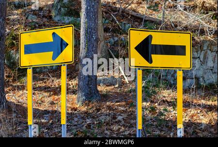 I cartelli stradali con frecce direzionali sembrano invitare confusione su una strada di campagna a Weston, Connecticut. Foto Stock
