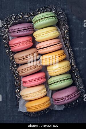 Macaron colorati al buio su un sfondo di legno Foto Stock
