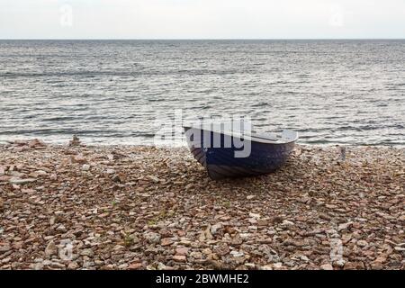 Barca a remi su una spiaggia rocciosa sul mare Foto Stock