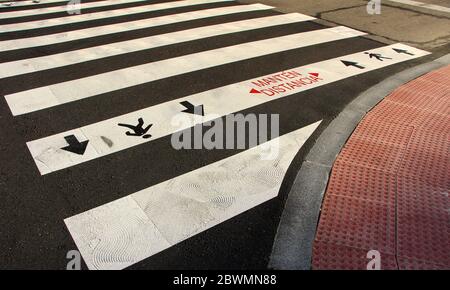 Primo piano di attraversamento zebra con nuove indicazioni per tenere separati durante il blocco in Spagna Manten Distancia (mantenere la distanza) Santander Spagna Foto Stock