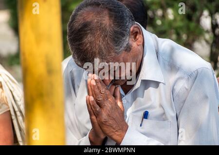 Nagpur, Maharashtra, India - 2019 marzo; un ritratto candido di un uomo indiano di mezza età che prega in un tempio buddista con le mani piegate. Foto Stock