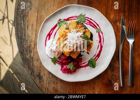 Pila di frittelle vegane decorate con banana, fetta di frutta drago, cioccolato e crema di cocco sul tavolo, vista dall'alto Foto Stock