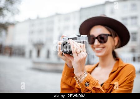 Ritratto di una giovane donna elegante con fotocamera in viaggio per la vecchia strada della città. Concetto di viaggio felice e vacanze estive nella città europea Foto Stock