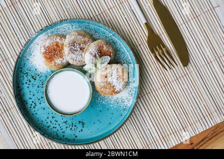Frittelle di formaggio tofu vegano su piatto blu con crema di cocco, vista dall'alto Foto Stock