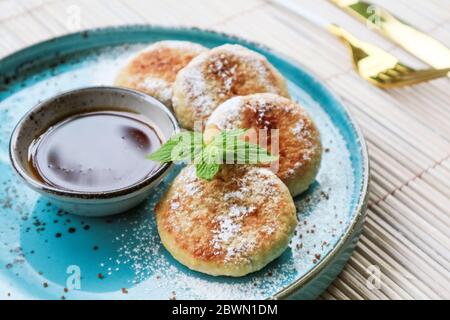 Frittelle di formaggio tofu vegano su piatto blu con chiocciola di miele Foto Stock