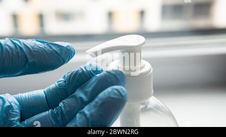 Sterilizzazione delle mani con guanti protettivi blu. Difese di base durante la pandemia COVID-19 Foto Stock