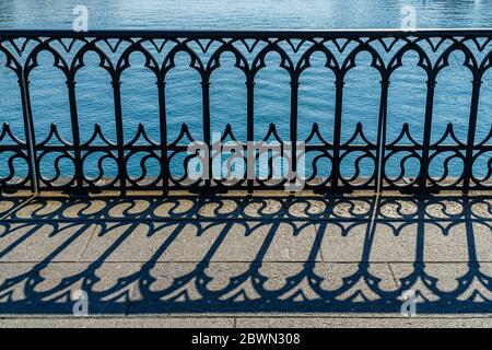 Primo piano della balaustra della Münsterbrücke Svizzera che forma un disegno interessante con la sua ombra sul terreno Foto Stock