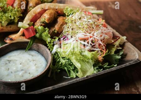 Falafel Pocket Pita. Spalmare con babaganoush, con coleslaw e falafel serviti con insalata a parte e tzatziki vegano. Foto Stock