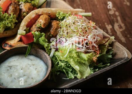 Falafel Pocket Pita. Spalmare con babaganoush, con coleslaw e falafel serviti con insalata a parte e tzatziki vegano. Foto Stock
