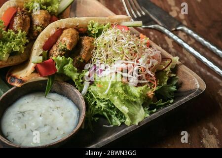 Falafel Pocket Pita. Spalmare con babaganoush, con coleslaw e falafel serviti con insalata a parte e tzatziki vegano. Foto Stock